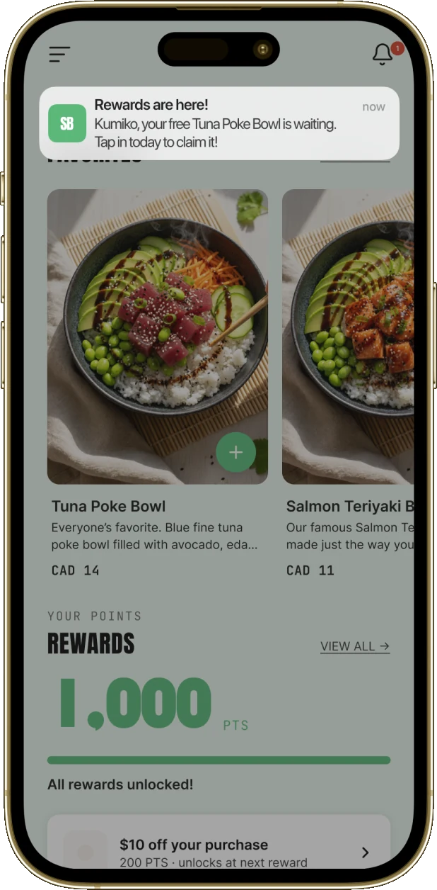 A guest's phone showing a campaign message arriving as a notification over the brand's app: “Rewards are here! Kumiko, your free Tuna Poke Bowl is waiting. Tap in today to claim it!”